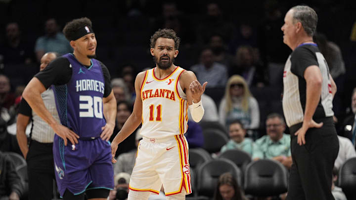 Mar 18, 2025; Charlotte, North Carolina, USA; Atlanta Hawks guard Trae Young (11) questions a call by referee Matt Boland (18) with Charlotte Hornets guard Seth Curry (30) during first quarter against the Charlotte Hornets at Spectrum Center. Mandatory Credit: Jim Dedmon-Imagn Images
