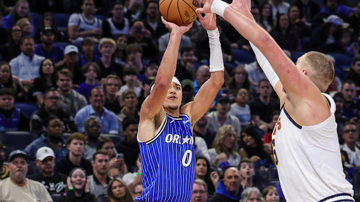 Dec 27, 2025; Orlando, Florida, USA; Orlando Magic guard Anthony Black (0) shoots a three point basket against Denver Nuggets center Nikola Jokic (15) during the first quarter at Kia Center. Mandatory Credit: Mike Watters-Imagn Images