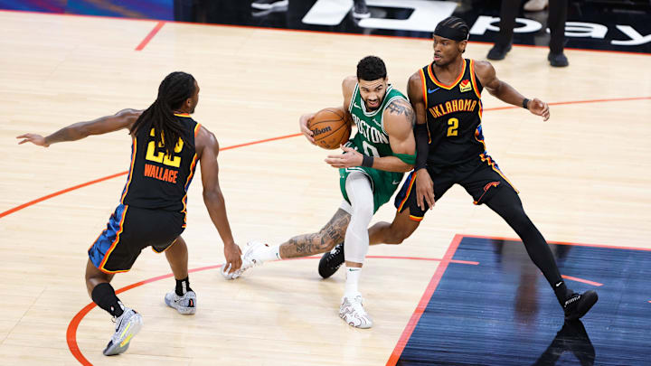 Jan 5, 2025; Oklahoma City, Oklahoma, USA; Boston Celtics forward Jayson Tatum (0) drives to the basket between Oklahoma City Thunder guard Cason Wallace (22) and guard Shai Gilgeous-Alexander (2) during the third quarter at Paycom Center. Mandatory Credit: Alonzo Adams-Imagn Images