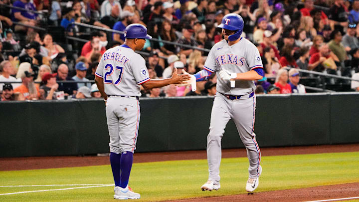 Sep 1, 2025; Phoenix, Arizona, USA; Texas Rangers catcher Kyle Higashioka (11) celebrates with Texas Rangers third base coach Tony Beasley (27) after Texas Rangers third base Cody Freeman (39) hits a home run to bring him home in the third inning during the game between the Texas Rangers and Arizona Diamondbacks at Chase Field. 