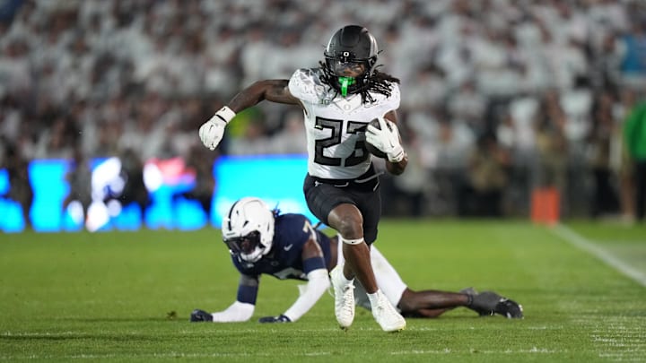 Sep 27, 2025; University Park, Pennsylvania, USA; Oregon Ducks running back Dierre Hill Jr. (23) runs for a gain after breaking a tackle by Penn State Nittany Lions cornerback Zion Tracy (7) during the third quarter at Beaver Stadium. Mandatory Credit: James Lang-Imagn Images