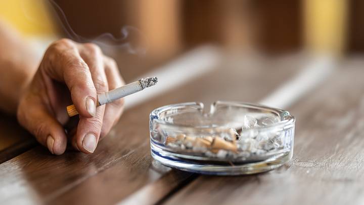 The hand of a smoking woman with a cigarette taps the ash into an ashtray. The hand of a smoking woman with a cigarette taps the ash into an ashtray.