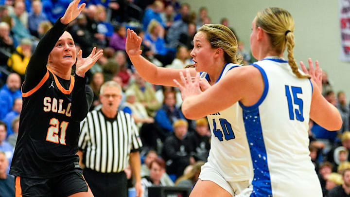 Solon’s Laeni Hinkle (21) passes the ball over Clear Creek Amana’s Lydia Keller (40) and Lena Evans (15) Dec. 5, 2025 during a girls basketball game in Tiffin, Iowa.