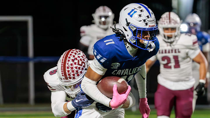 Caravel defensive back Richie Massey (left) dives to bring down Middletown receiver DJ Davis after a catch and run in the first quarter of the Cavaliers’ 28-7 win over the Buccaneers at Cavalier Stadium on Oct. 17, 2025.