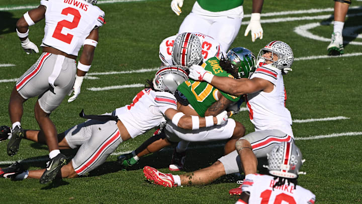 Jan 1, 2025; Pasadena, CA, USA; Oregon Ducks running back Jordan James (20) is stopped by Ohio State Buckeyes cornerback Jordan Hancock (7), Ohio State Buckeyes linebacker Kourt Williams II (2) and Brown Ohio State Buckeyes defensive end Jack Sawyer (33) during the first quarter at Rose Bowl Stadium. Mandatory Credit: Robert Hanashiro-Imagn Images