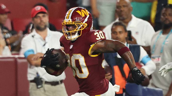 Aug 14, 2026; Landover, Maryland, USA; Washington Commanders running back Robert Henry Jr. (30) carries the ball past Miami Dolphins cornerback Marco Wilson (21) en route to a touchdown during the first half at Northwest Stadium. Mandatory Credit: Geoff Burke-Imagn Images