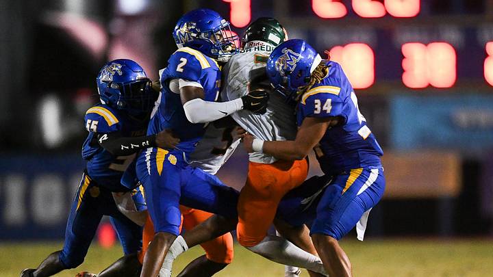 Martin County's Amarion Queen (2) and Tyrone Robinson (34) tackle McArthur's Kenson Louis (2) in a Region 4-5A quarterfinal football game, Nov. 14, 2025, at Martin County High School. McArthur won 41-13. Martin County's Amarion Queen (2) and Tyrone Robinson (34) tackle McArthur's Kenson Louis (2) in a Region 4-5A quarterfinal football game, Nov. 14, 2025, at Martin County High School. McArthur won 41-13.