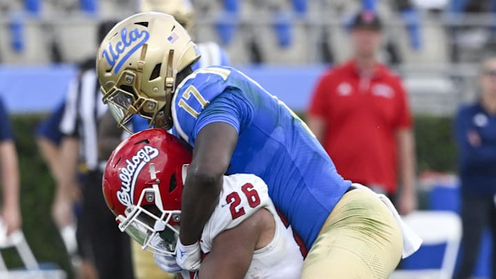 Nov 30, 2024; Pasadena, California, USA; UCLA Bruins linebacker Carson Schwesinger (49) and linebacker Jalen Woods (17) tackle Fresno State Bulldogs running back Bryson Donelson (26) in the third quarter at Rose Bowl. Mandatory Credit: Robert Hanashiro-Imagn Images