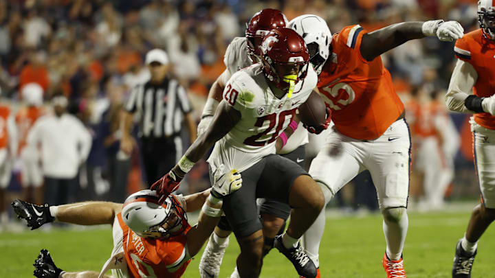 Oct 18, 2025; Charlottesville, Virginia, USA; Washington State Cougars running back Leo Pulalasi (20) carries the ball as Virginia Cavaliers safety Ethan Minter (30) attempts a tackle during the first half at Scott Stadium. Mandatory Credit: Geoff Burke-Imagn Images