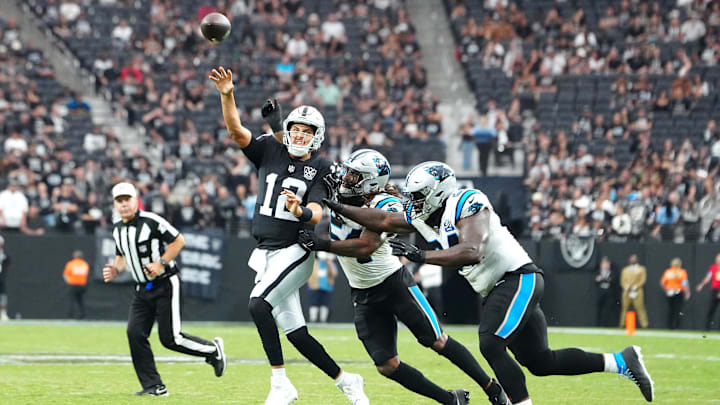 Sep 22, 2024; Paradise, Nevada, USA; Las Vegas Raiders quarterback Aidan O'Connell (12) makes a touchdown pass under pressure from Carolina Panthers linebacker Shaq Thompson (54) and Carolina Panthers defensive end A'Shawn Robinson (94) during the fourth quarter at Allegiant Stadium. Mandatory Credit: Stephen R. Sylvanie-Imagn Images