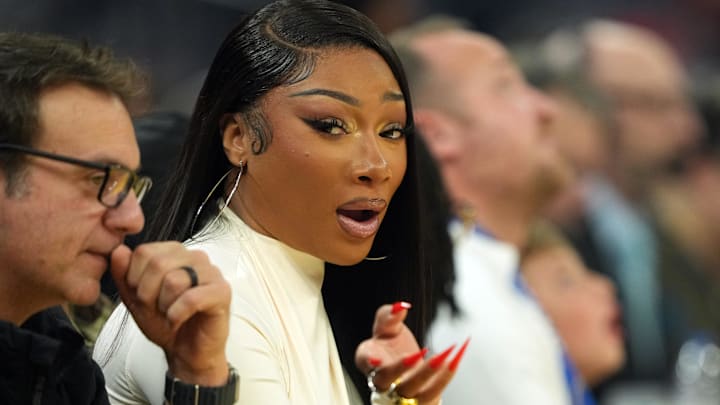 Dec 25, 2025; San Francisco, California, USA; Recording artist Megan Thee Stallion (center left) sits courtside during the first quarter of the game between the Golden State Warriors and the Dallas Mavericks at Chase Center.