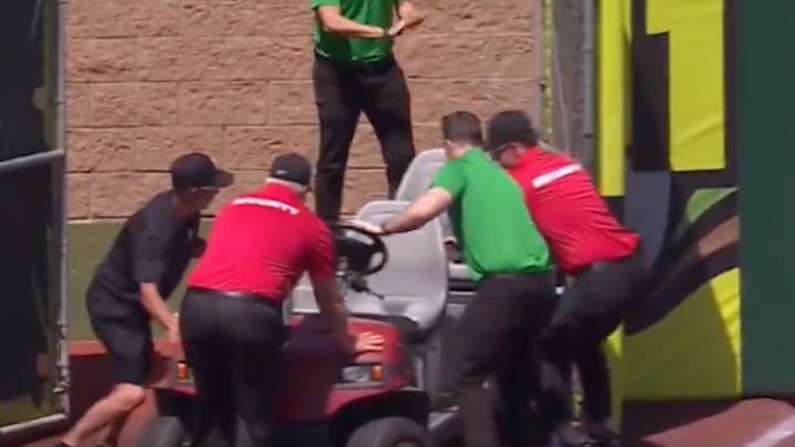Employees at Sutter Health Park attempt to push a golf cart through a gate in the outfield. 