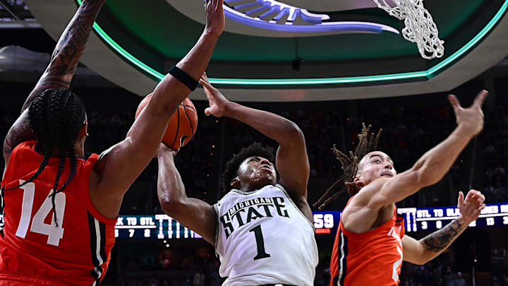 Jan 19, 2025; East Lansing, Michigan, USA;  Michigan State Spartans guard Jeremy Fears Jr. (1) splits Illinois Fighting Illini guard Kylan Boswell (14) and Illinois Fighting Illini guard Dra Gibbs-Lawhorn (2) on his way to a basket during the second half  at Jack Breslin Student Events Center. Mandatory Credit: Dale Young-Imagn Images