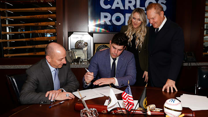Carlos Rodón junto a su esposa y ejecutivos de los Yankees de Nueva York, en la firma de su contrato