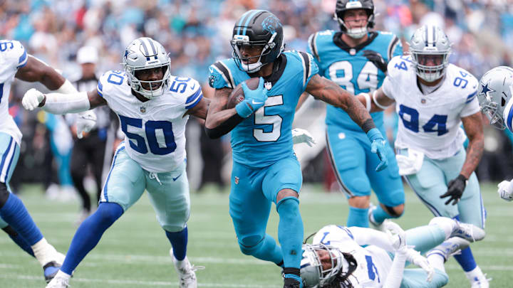 Oct 12, 2025; Charlotte, North Carolina, USA; Carolina Panthers running back Rico Dowdle (5) runs with the ball while getting pressured by Dallas Cowboys linebacker Shemar James (50) during the second half at Bank of America Stadium. Mandatory Credit: Scott Kinser-Imagn Images