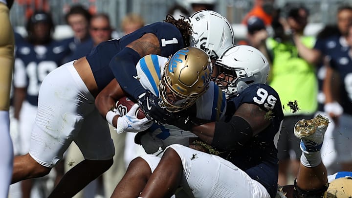 Oct 5, 2024; University Park, Pennsylvania, USA; Penn State Nittany Lions defensive tackle Coziah Izzard (99) and safety Jaylen Reed (1) stop UCLA Bruins running back Jalen Berger (0) during the third quarter at Beaver Stadium. Mandatory Credit: Matthew O'Haren-Imagn Images