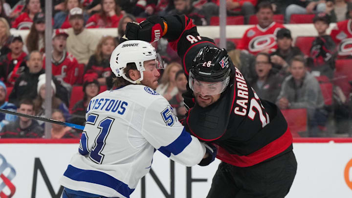 Feb 26, 2026; Raleigh, North Carolina, USA;  Carolina Hurricanes left wing William Carrier (28) and Tampa Bay Lightning defenseman Charle-Edouard D'Astous (51) battle during the third period at Lenovo Center. Mandatory Credit: James Guillory-Imagn Images