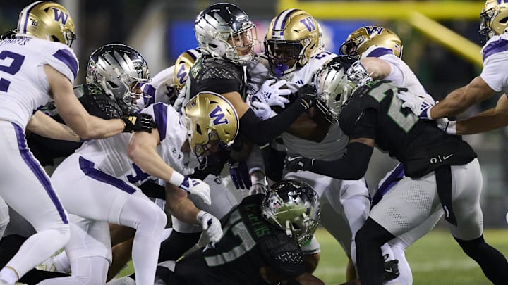Nov 30, 2024; Eugene, Oregon, USA; Washington Huskies running back Daniyel Ngata (21) carries the ball as he is stopped by Oregon Ducks defensive back Peyton Woodyard (12) during the second half at Autzen Stadium. Mandatory Credit: Troy Wayrynen-Imagn Images