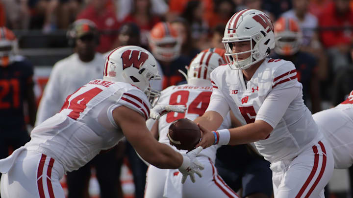 Oct 9, 2021; Champaign, Illinois, USA; Wisconsin Badgers quarterback Graham Mertz (5) hands the ball to Wisconsin Badgers fullback John Chenal (44) in the first half of Saturday's game with the Illinois Fighting Illini at Memorial Stadium. Oct 9, 2021; Champaign, Illinois, USA; Wisconsin Badgers quarterback Graham Mertz (5) hands the ball to Wisconsin Badgers fullback John Chenal (44) in the first half of Saturday's game with the Illinois Fighting Illini at Memorial Stadium.