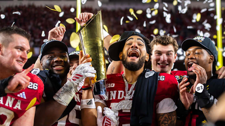 Indiana's Elijah Sarratt (13), and Tyrique Tucker (95) with Ferenando Memdoza (15) behind them hoist the trophy after the College Football Playoff National Championship college football game at Hard Rock Stadium in Miami Gardens on Monday, Jan. 19, 2026.