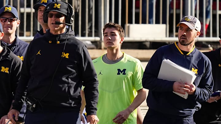 Michigan Wolverines head coach Jim Harbaugh watches from the sideline beside off-field analyst