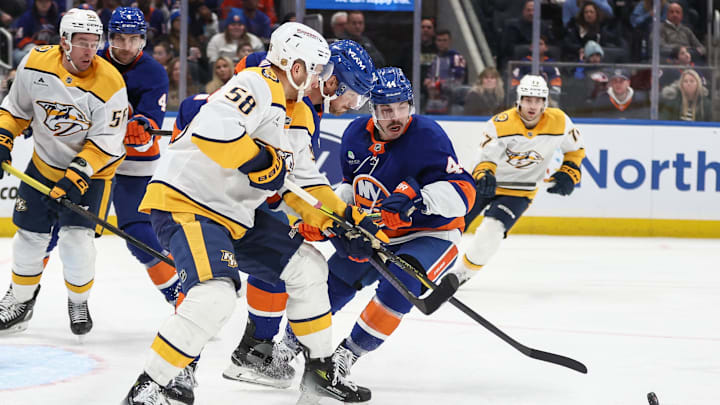 Jan 31, 2026; Elmont, New York, USA;  Nashville Predators left wing Michael Bunting (58) battles for control of the puck with New York Islanders defenseman Scott Mayfield (24) and center Jean-Gabriel Pageau (44) in the third period at UBS Arena. Mandatory Credit: Wendell Cruz-Imagn Images