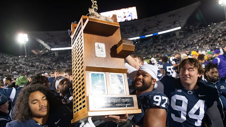 Penn State Nittany Lions football players lift up the Land Grant Trophy after defeating the Michigan State Spartans in 2022. 