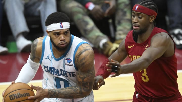 Mar 25, 2024; Cleveland, Ohio, USA; Charlotte Hornets forward Miles Bridges (0) looks to pass beside Cleveland Cavaliers guard Caris LeVert (3) in the fourth quarter at Rocket Mortgage FieldHouse. Mandatory Credit: David Richard-USA TODAY Sports