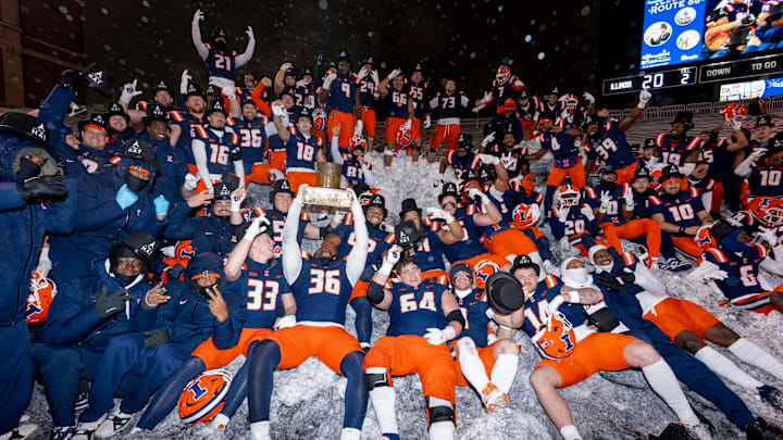 The Illinois football team gathers on the snow mounds inside Gies Memorial Stadium after its 20-13 win over Northwestern on Saturday in its season finale in Champaign, Illinois.