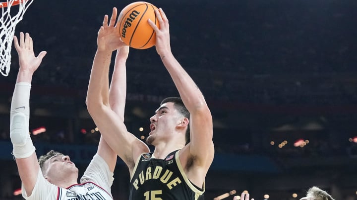 Connecticut Huskies center Donovan Clingan (32) and Connecticut Huskies guard Cam Spencer (12) defend the shot of Purdue Boilermakers center Zach Edey (15) during the NCAA Men’s Basketball Tournament Championship, Monday, April 8, 2024, at State Farm Stadium in Glendale, Ariz.