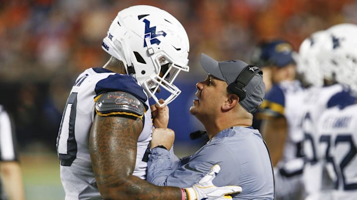 Dec 28, 2018; Orlando, FL, USA; West Virginia Mountaineers defensive lineman Kenny Bigelow Jr. (40) gets a talking to from defensive coordinator Tony Gibson (right) following a Syracuse Orange touchdown during the second quarter in the 2018 Camping World Bowl at Camping World Stadium. Mandatory Credit: Reinhold Matay-Imagn Images