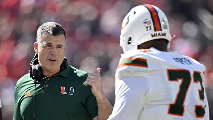 Oct 19, 2024; Louisville, Kentucky, USA; Miami Hurricanes head coach Mario Cristobal talks with offensive lineman Anez Cooper (73) during the first half against the Louisville Cardinals at L&N Federal Credit Union Stadium. Mandatory Credit: Jamie Rhodes-Imagn Images Oct 19, 2024; Louisville, Kentucky, USA; Miami Hurricanes head coach Mario Cristobal talks with offensive lineman Anez Cooper (73) during the first half against the Louisville Cardinals at L&N Federal Credit Union Stadium. Mandatory Credit: Jamie Rhodes-Imagn Images