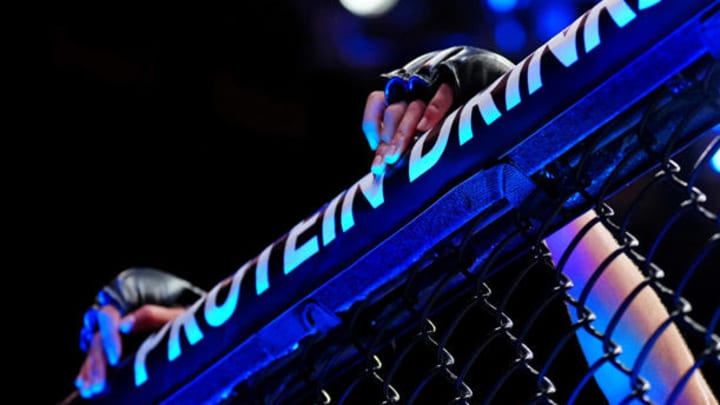 UFC fighter's hands on the cage.