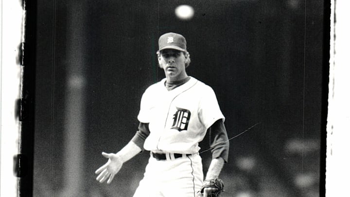 Former Detroit Tigers pitcher Mike Henneman looks on wearing a white jersey and navy blue hat.