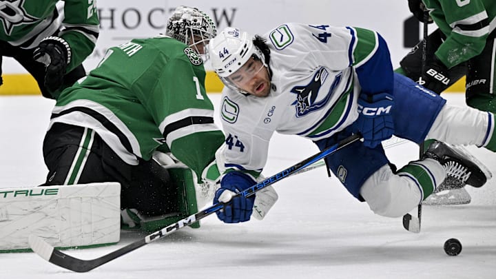 Apr 8, 2025; Dallas, Texas, USA; Vancouver Canucks left wing Kiefer Sherwood (44) attempts to poke the puck past Dallas Stars goaltender Casey DeSmith (1) during the first period at the American Airlines Center. Mandatory Credit: Jerome Miron-Imagn Images