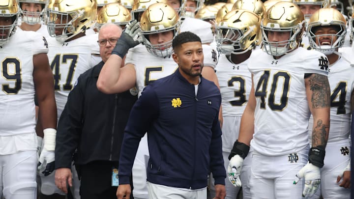Notre Dame Fighting Irish head coach Marcus Freeman (middle) leads the team onto the field