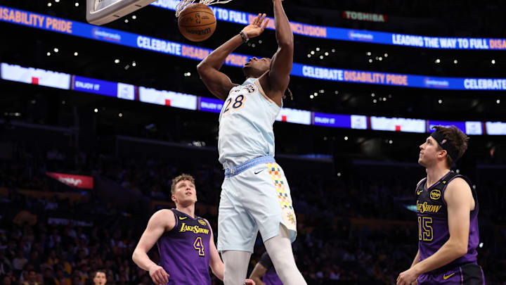 Jan 13, 2025; Los Angeles, California, USA;  San Antonio Spurs center Charles Bassey (28) dunks a ball against Los Angeles Lakers guard Dalton Knecht (4) and guard Austin Reaves (15) during the second half at Crypto.com Arena. Mandatory Credit: Kiyoshi Mio-Imagn Images