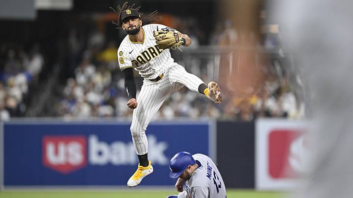 May 20, 2026; San Diego, California, USA; San Diego Padres second baseman Fernando Tatis Jr. (23) throws over Los Angeles Dodgers third baseman Max Muncy (13) as he turns a double play during the eighth inning at Petco Park. Mandatory Credit: Denis Poroy-Imagn Images