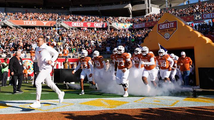 Texas Longhorns head coach Steve Sarkisian, Texas Longhorns wide receiver Parker Livingstone (13) and offensive lineman Brandon Baker (73) run onto the field before a game against the Michigan Wolverines at Camping World Stadium.