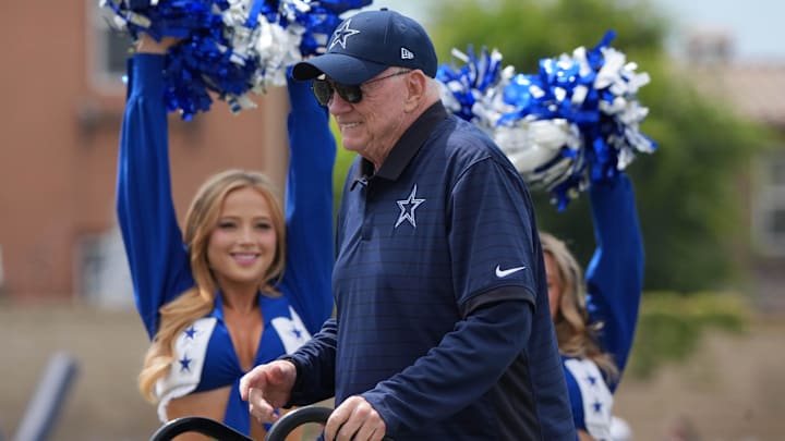 Dallas Cowboys owner Jerry Jones walks past cheerleaders at training camp opening ceremonies at the River Ridge Fields.