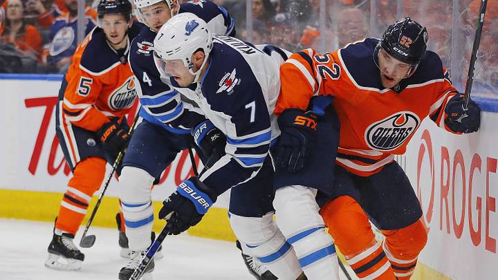 Feb 29, 2020; Edmonton, Alberta, CAN; Winnipeg Jets defensemen Dmitry Kulikov (7) and Edmonton Oilers forward Patrick Russell (52) battle along the boards for a loose puck during the first period at Rogers Place. Mandatory Credit: Perry Nelson-Imagn Images