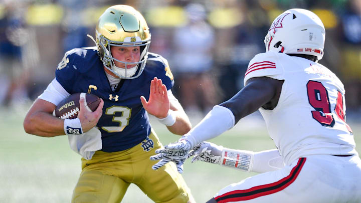 Sep 21, 2024; South Bend, Indiana, USA; Notre Dame Fighting Irish quarterback Riley Leonard (13) runs the ball as Miami Redhawks defensive end Josh Lukusa (94) defends in the second quarter at Notre Dame Stadium. Mandatory Credit: Matt Cashore-Imagn Images