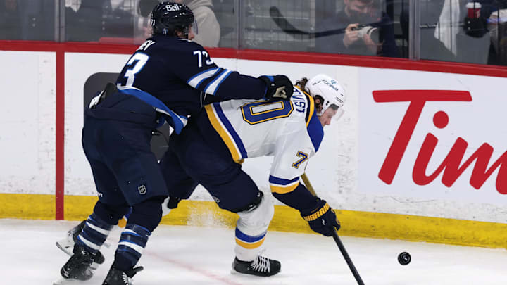 Apr 21, 2025; Winnipeg, Manitoba, CAN; Winnipeg Jets left wing Brandon Tanev (73) checks St. Louis Blues center Oskar Sundqvist (70) in the third period in game two of the first round of the 2025 Stanley Cup Playoffs at Canada Life Centre. Mandatory Credit: James Carey Lauder-Imagn Images