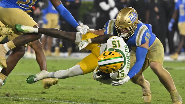 Sep 28, 2024; Pasadena, California, USA; Oregon Ducks wide receiver Tez Johnson (15) is sent flying through the air as UCLA Bruins linebacker Carson Schwesinger (49) makes the tackle in the fourth quarter at Rose Bowl. Mandatory Credit: Robert Hanashiro-Imagn Images
