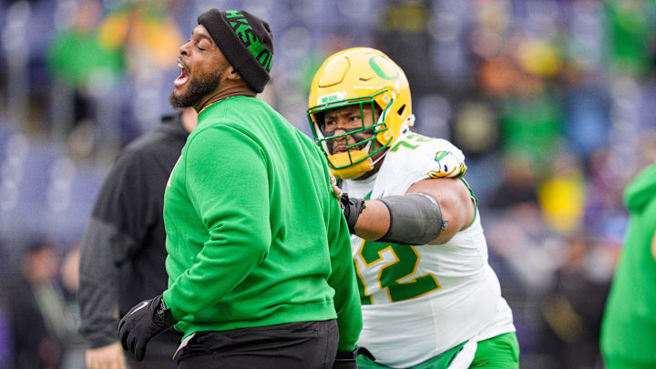 Oregon offensive line coach A'lique Terry, left, works with Oregon offensive lineman Iapani Laloulu during warmups as the Oregon Ducks take on the Washington Huskies on Nov. 29, 2025, at Husky Stadium in Seattle, Washington.
