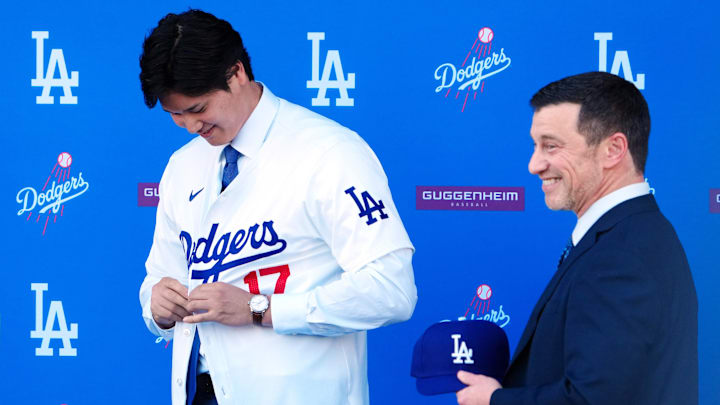 Dodgers player Shohei Ohtani receives a Dodgers cap from president of baseball operations Andrew Friedman at an introductory press conference at Dodger Stadium on Dec. 14, 2023.