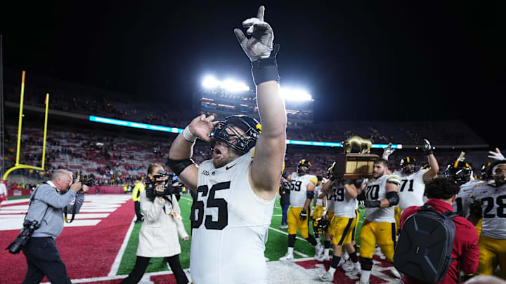 Oct 11, 2025; Madison, Wisconsin, USA; Iowa Hawkeyes offensive lineman Logan Jones (65) celebrates a win after the game against the Wisconsin Badgers while teammates carry The Heartland Trophy in the background at Camp Randall Stadium. Mandatory Credit: Ross Harried-Imagn Images
