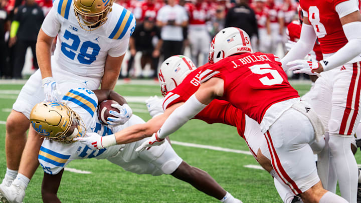 Nov 2, 2024; Lincoln, Nebraska, USA; UCLA Bruins running back T.J. Harden (25) dives forward against Nebraska Cornhuskers defensive back Isaac Gifford (2) and linebacker John Bullock (5) during the first quarter at Memorial Stadium. Mandatory Credit: Dylan Widger-Imagn Images