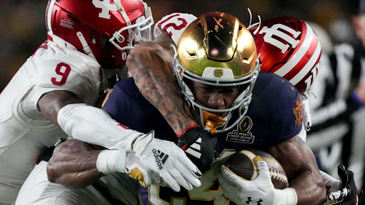 Indiana Hoosiers defensive back Jamier Johnson (9) and defensive back Terry Jones Jr. (12) tackle Notre Dame Fighting Irish running back Jadarian Price (24) during the first half of a game between the Indiana Hoosiers and the Notre Dame Fighting Irish in first round of the College Football Playoff on Friday, Dec. 20, 2024, in South Bend.