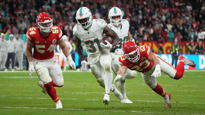 Nov 5, 2023; Frankfurt, Germany; Miami Dolphins running back Raheem Mostert (31) carries the ball on a 13-yard touchdown run against Kansas City Chiefs linebacker Leo Chenal (54) and linebacker Drue Tranquill (23) in the second half during an NFL International Series game at Deutsche Bank Park. Mandatory Credit: Kirby Lee-Imagn Images
